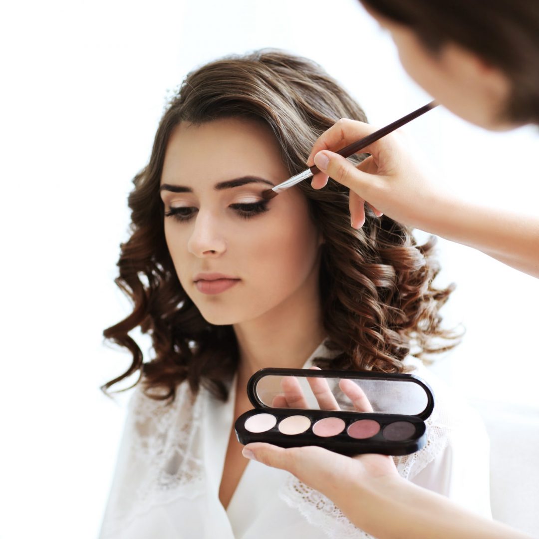 Makeup artist preparing bride before her wedding